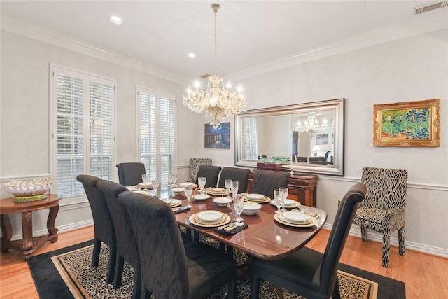 dining area featuring baseboards, visible vents, ornamental molding, light wood-type flooring, and a chandelier