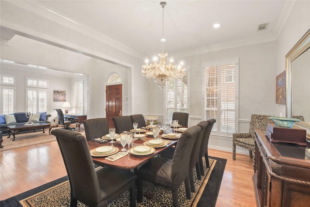 dining area with ornamental molding, light wood finished floors, visible vents, and a wealth of natural light