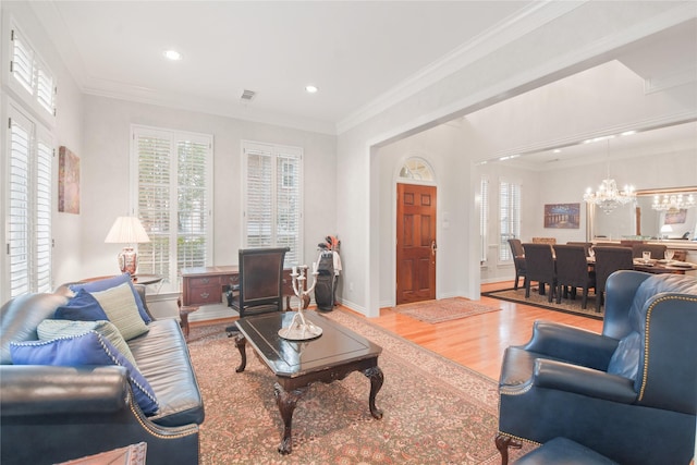 living room with light wood finished floors, a chandelier, a wealth of natural light, and crown molding