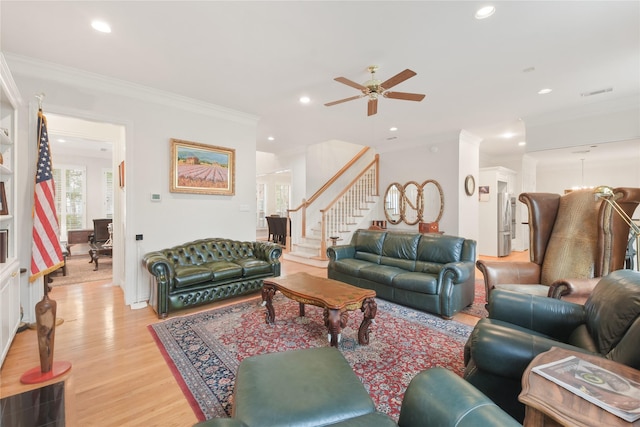 living room featuring recessed lighting, crown molding, light wood-style flooring, and stairs