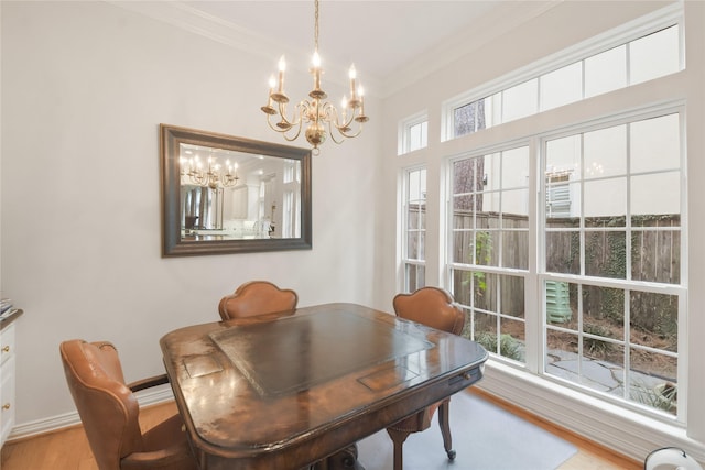 dining room featuring a chandelier, ornamental molding, light wood-style flooring, and baseboards