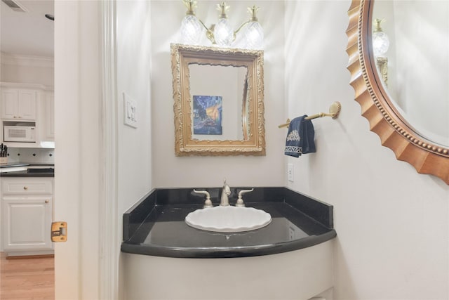 bathroom with visible vents, ornamental molding, wood finished floors, and vanity