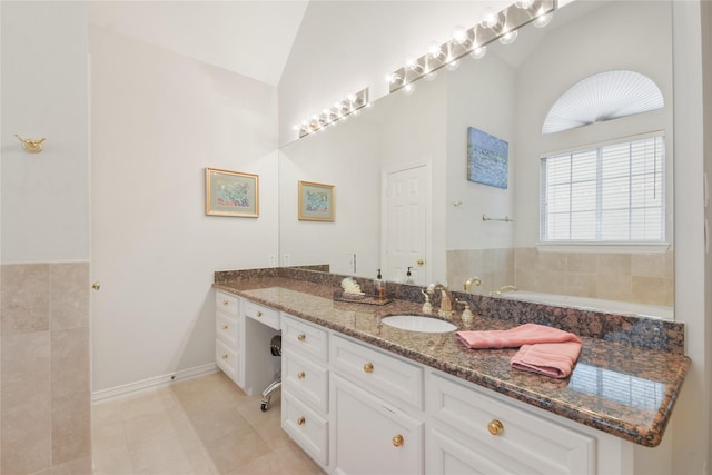 full bath featuring tile patterned floors, vaulted ceiling, vanity, baseboards, and a bath