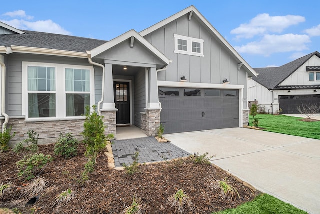 modern farmhouse style home featuring concrete driveway, stone siding, roof with shingles, an attached garage, and board and batten siding