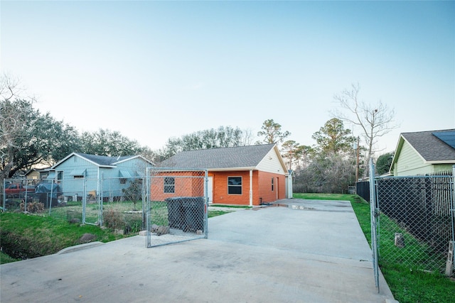 rear view of house featuring brick siding, fence, and driveway