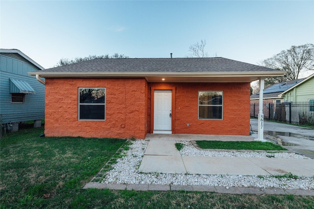 bungalow-style home featuring a shingled roof, a front yard, and fence