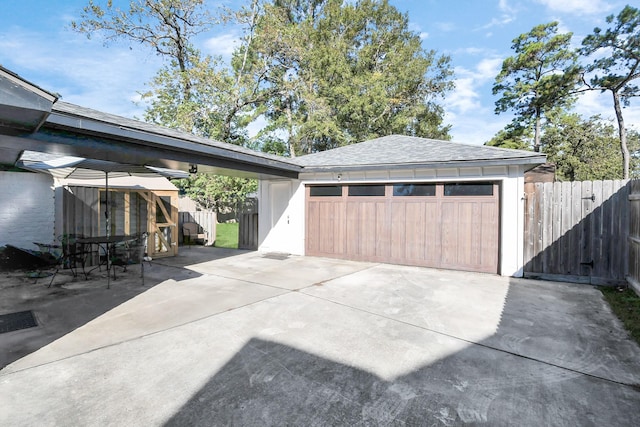 garage featuring concrete driveway and fence