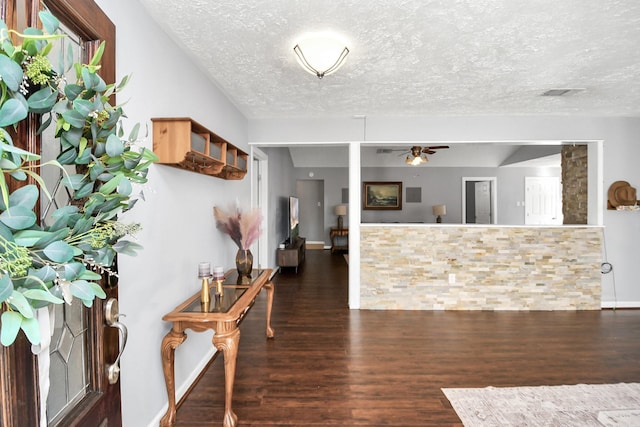 entryway with dark wood-type flooring, visible vents, ceiling fan, and a textured ceiling