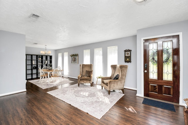 foyer with a notable chandelier, dark wood finished floors, a textured ceiling, and baseboards