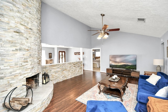 living area with visible vents, ceiling fan, wood finished floors, a textured ceiling, and a fireplace