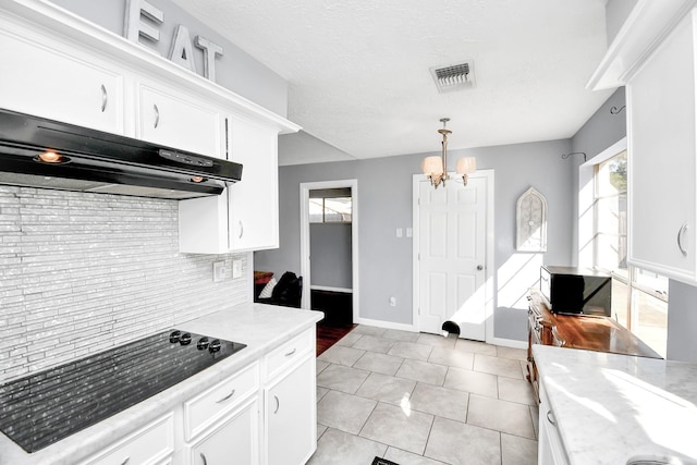 kitchen featuring visible vents, pendant lighting, white cabinets, and under cabinet range hood