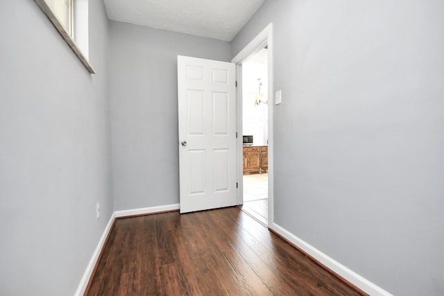 spare room featuring dark wood-type flooring, a textured ceiling, and baseboards