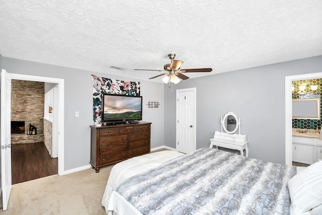 bedroom with light carpet, a fireplace, a textured ceiling, and ceiling fan