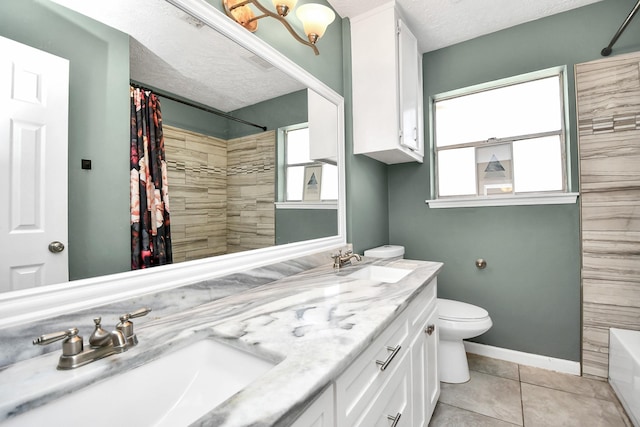 bathroom with a textured ceiling, tile patterned floors, a sink, and a healthy amount of sunlight