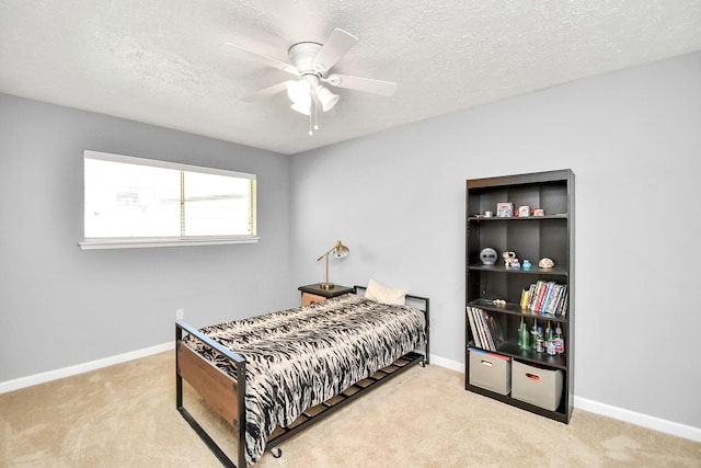 bedroom with a ceiling fan, baseboards, a textured ceiling, and light colored carpet