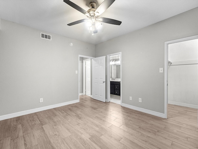 unfurnished bedroom featuring a spacious closet, light wood-type flooring, visible vents, and baseboards