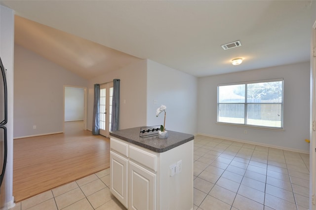 kitchen with light tile patterned floors, visible vents, dark countertops, lofted ceiling, and open floor plan