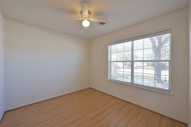 unfurnished room featuring light wood-style floors, visible vents, baseboards, and a ceiling fan