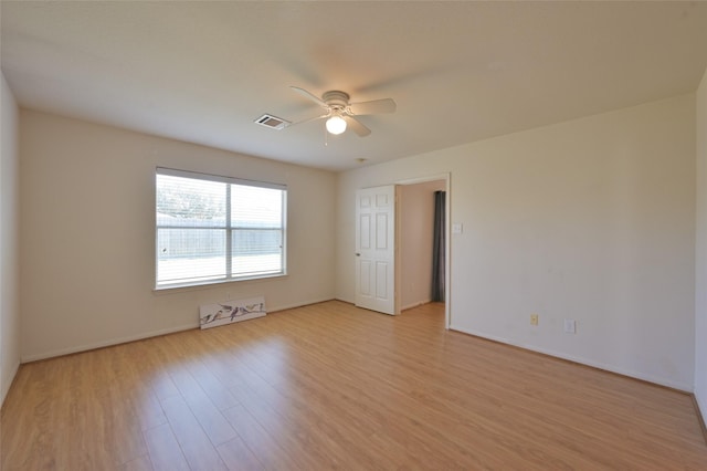 empty room featuring ceiling fan, baseboards, visible vents, and light wood-style floors