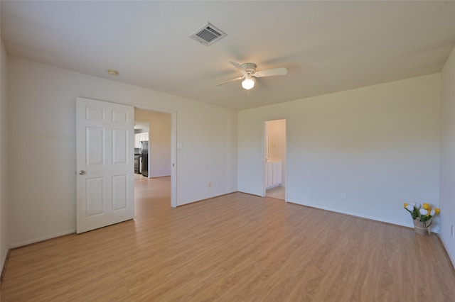 empty room featuring light wood-type flooring, visible vents, and a ceiling fan