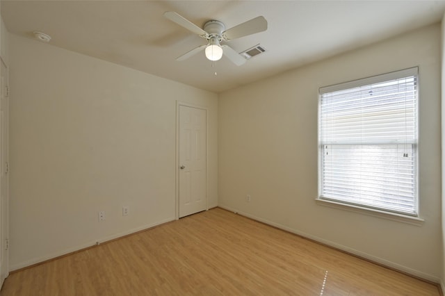 spare room with ceiling fan, light wood-type flooring, visible vents, and baseboards