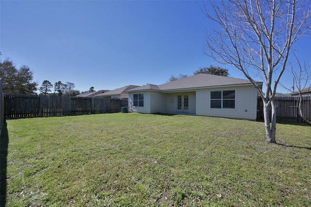 rear view of property featuring a yard and a fenced backyard