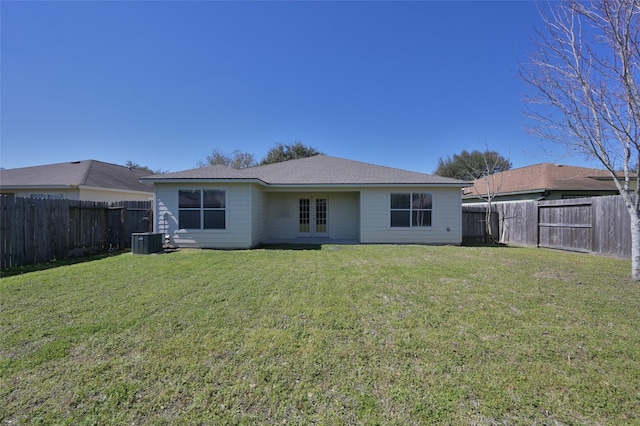 rear view of house with french doors, a fenced backyard, a yard, and central AC unit