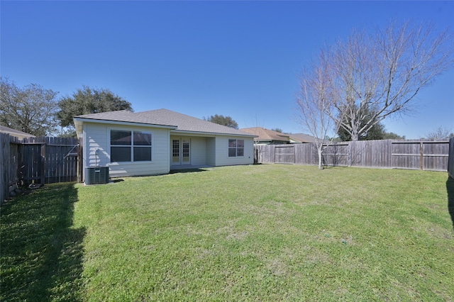 back of house with central AC unit, a lawn, and a fenced backyard