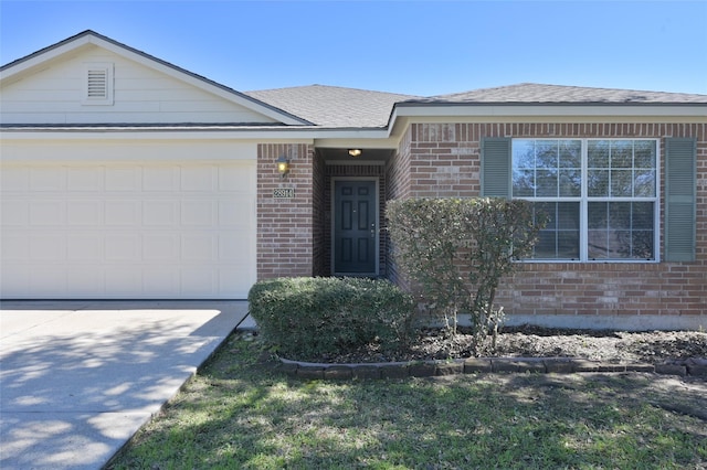 ranch-style house with an attached garage, a shingled roof, concrete driveway, and brick siding