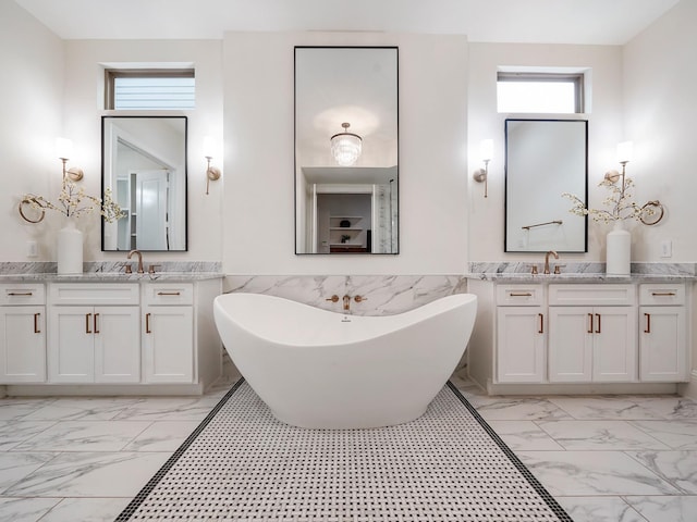 full bath featuring a sink, two vanities, marble finish floor, and a freestanding bath