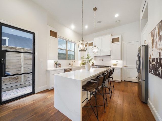 kitchen featuring a kitchen island, decorative light fixtures, stainless steel appliances, light countertops, and white cabinetry