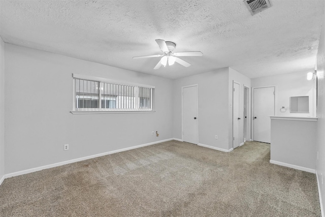 carpeted spare room featuring a ceiling fan, visible vents, a textured ceiling, and baseboards