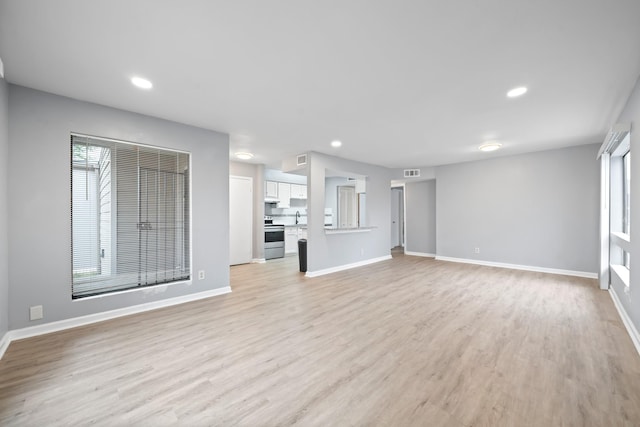 unfurnished living room featuring light wood finished floors, baseboards, visible vents, and recessed lighting