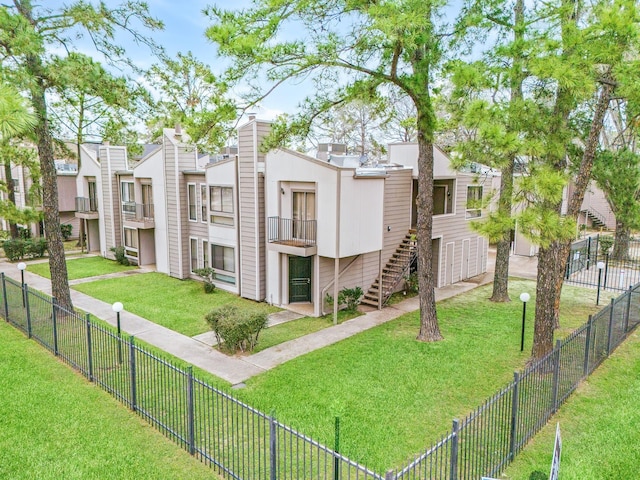 exterior space featuring a residential view, stairway, a front lawn, and fence