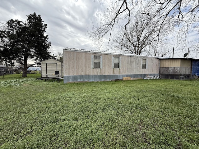 back of house with a shed, metal roof, a lawn, and an outbuilding