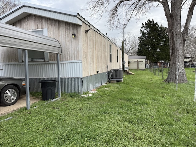 view of side of property with central AC unit, an outbuilding, and a yard