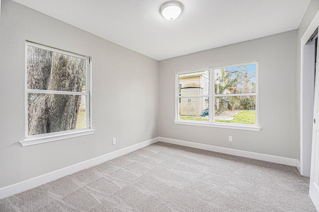 empty room featuring light carpet and baseboards