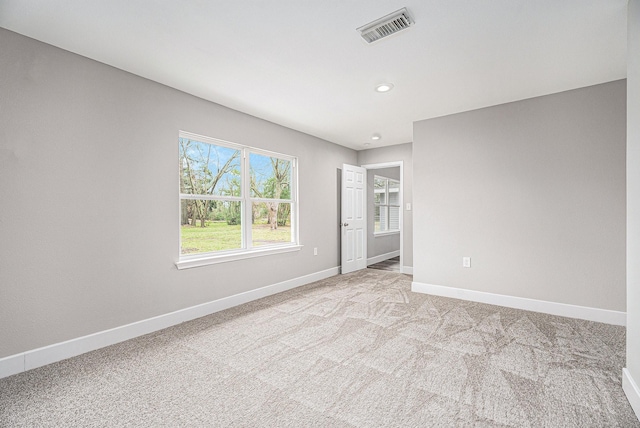 spare room featuring light colored carpet, visible vents, baseboards, and recessed lighting