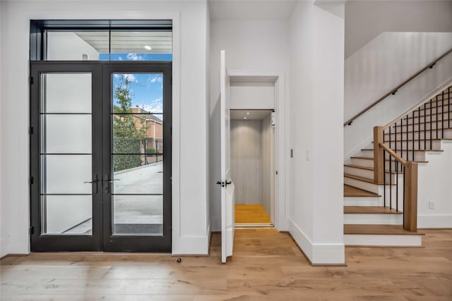 interior space featuring stairs, french doors, light wood-style flooring, and baseboards