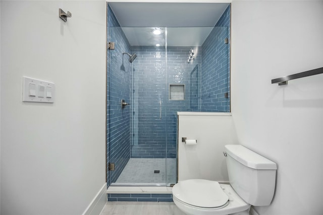 full bath with a stall shower, baseboards, and toilet