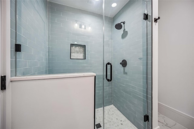 bathroom featuring marble finish floor, a shower stall, and baseboards