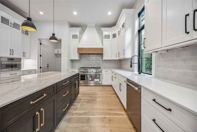 kitchen featuring stainless steel appliances, white cabinetry, and custom range hood