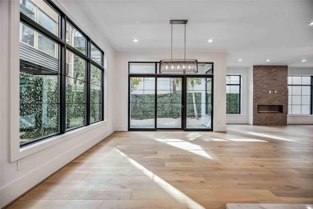 interior space with a large fireplace, recessed lighting, light wood-style flooring, and baseboards