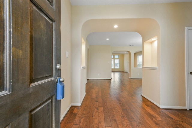 entryway featuring dark wood-style floors, arched walkways, and baseboards