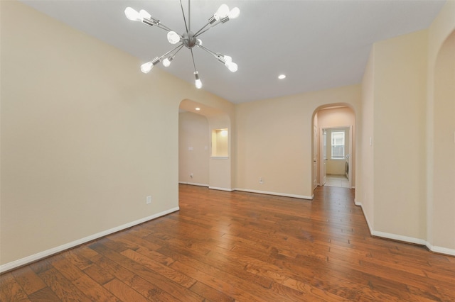 empty room with dark wood-style floors, arched walkways, and baseboards