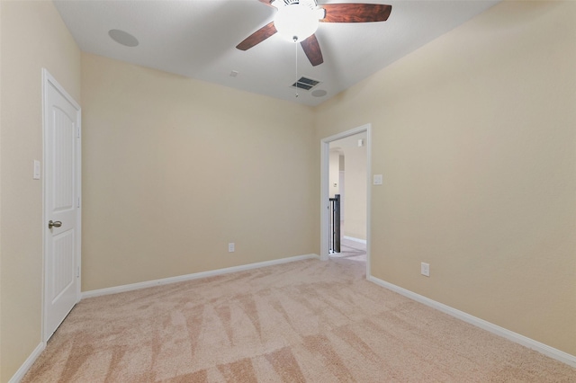 spare room featuring light carpet, a ceiling fan, visible vents, and baseboards