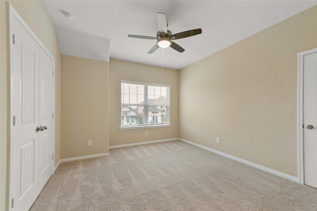 unfurnished bedroom featuring light carpet, baseboards, and a ceiling fan