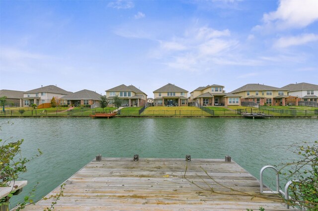 dock area with a lawn, a water view, and a residential view