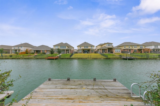 view of dock featuring a water view, a residential view, and fence