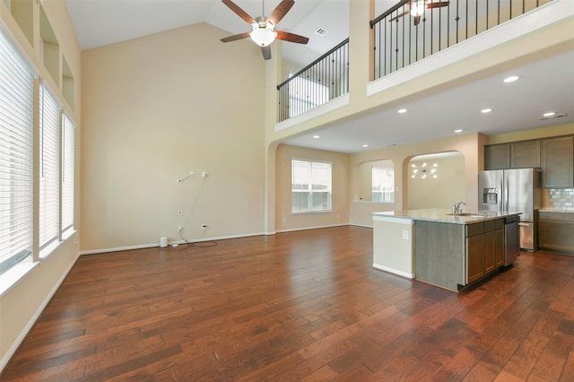 24030 Tirso River Ct, Katy, TX 77493 - kitchen with ceiling fan with notable chandelier, high vaulted ceiling, dark wood-type flooring, arched walkways, and open floor plan
